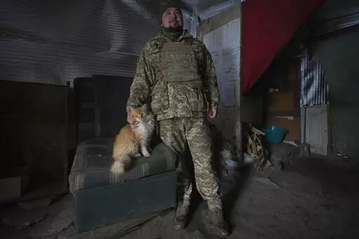 An Ukrainian serviceman pats Vasiliy the cat at an advanced position on the front line in the Luhansk area, eastern Ukraine, Thursday, Jan. 27, 2022. The U.S. rejection of Russia's main demands to resolve the crisis over Ukraine left "little ground for optimism," the Kremlin said Thursday, but added that dialogue was still possible. (AP Photo/Vadim Ghirda)
