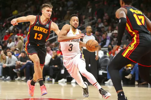 New Orleans Pelicans guard CJ McCollum (3) drives past Atlanta Hawks guard Bogdan Bogdanovic (13) and forward Onyeka Okongwu (17) in the first half of an NBA basketball game Sunday, March 20, 2022, in Atlanta, Ga. (AP Photo/Brett Davis)