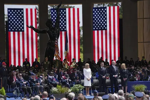 French President Emmanuel Macron, 2nd left, his wife Brigitte Macron, left, and US President Joe Biden, center right, and first lady Jill Biden attend a ceremony together with World War II veterans at an US cemetery near Colleville-sur-Mer Normandy, Thursday, June 6, 2024. World War II veterans from across the United States as well as Britain and Canada are in Normandy this week to mark 80 years since the D-Day landings that helped lead to Hitler's defeat. (AP Photo/Laurent Cipriani)