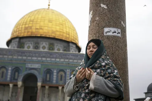 A woman prays at the Al-Aqsa Mosque compound during the first Friday Prayers of the Muslim holy month of Ramadan in the Old City of Jerusalem, Friday, March 7, 2025. Arabic on top right reads: "Pray for the Prophet." (AP Photo/Mahmoud Illean)