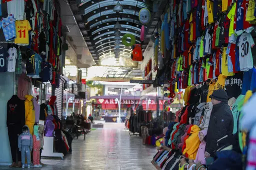 A clothes shop keeper waits for clients in a deserted tourist shopping area in Belek, Antalya, Turkey, Saturday, March 12, 2022. After losing two years to the COVID-19 pandemic, shopkeepers in the heart of the Turkish Riviera had hoped for a strong tourism season this year to help keep their businesses afloat. But Russia's war in Ukraine is fast dampening their spirits. (AP Photo/Riza Ozel)