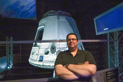 Kyle Hippchen, a Florida-based airline captain, poses for a photo in front of a SpaceX Dragon capsule at the Kennedy Space Center Visitor Complex in Cape Canaveral, Fla., Friday, Jan. 21, 2022. Hippchen, the real winner of a first-of-its-kind sweepstakes, gave his seat on a SpaceX flight to his college roommate. Though his secret is finally out, that doesn’t make it any easier knowing he missed his chance to orbit Earth because he exceeded the weight limit. (AP Photo/John Raoux)