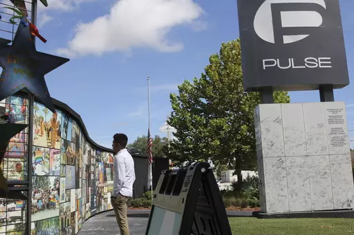 Brandon Wolf, a survivor of the Pulse nightclub shooting and activist, looks at the photos that are a part of the Pulse memorial in Orlando, Fla., on Sept. 9, 2022. The city of Orlando plans to purchase the gay nightclub property where 49 people were massacred seven years ago, in what at the time was the deadliest mass shooting in modern U.S. history, with the intention of building a memorial for the victims, Mayor Buddy Dyer said Wednesday, Oct. 18, 2023. (AP Photo/Cody Jackson, file)