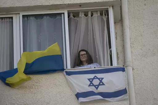 Tatyana Prima, who fled Mariupol, Ukraine, poses for a portrait with her national flag and the Israeli flag she displays outside of her apartment window in Ashkelon, southern Israel, Wednesday, Nov. 8, 2023. She thought she'd left the bombs behind when she fled after Russian troops decimated her city. Risking her life, the 38-year-old escaped with her injured husband and young daughter, bringing the family to safety in southern Israel. Yet the calm she was slowly regaining shattered on Oct. 7, w