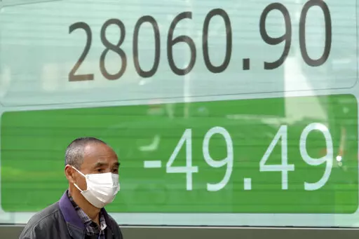 A man wearing a protective mask walks in front of an electronic stock board showing Japan's Nikkei 225 index at a securities firm Friday, March 25, 2022, in Tokyo. Asian stock markets fell Friday after Western governments promised new sanctions on Russia and President Vladimir Putin tried to prop up Moscow's sinking ruble by threatening to require Europe to use it to pay for gas exports. (AP Photo/Eugene Hoshiko)