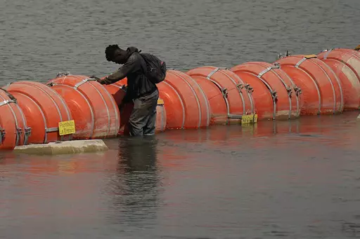 A migrant from Columbia stands at a floating buoy barrier as he looks to cross the Rio Grande from Mexico into the U.S., Monday, Aug. 21, 2023, in Eagle Pass, Texas. (AP Photo/Eric Gay)