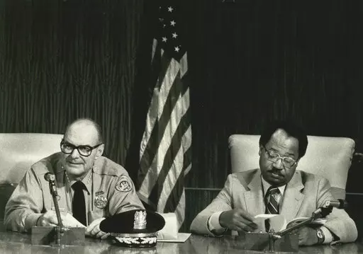 Retiring police Chief Henry Morris, left, and new Chief Warren Woodfork sit in the City Council chambers Wednesday, Jan. 16, 1985, prior to an awards ceremony for 1984's outstanding police officers. The New Orleans Police Department says its first Black superintendent has died. A tweet from the department says Warren Woodfork Sr. died Wednesday, March 9, 2022. The Times-Picayune/The New Orleans Advocate reports that he was 85 years old. (G. Andrew Boyd/The Times-Picayune/The New Orleans Advocate