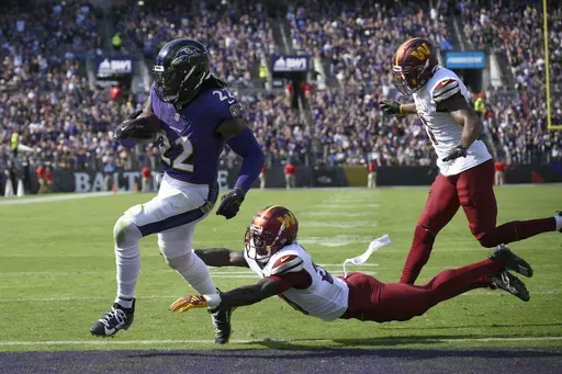 Baltimore Ravens running back Derrick Henry (22) scores past Washington Commanders safety Quan Martin and safety Jeremy Chinn, right, during the first half of an NFL football game Sunday, Oct. 13, 2024, in Baltimore. (AP Photo/Nick Wass)