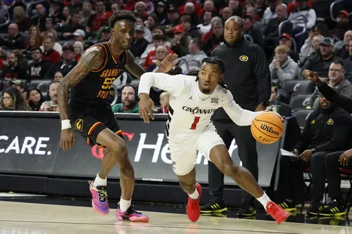 Cincinnati's Day Day Thomas, right, dribbles past Grambling State's Ernest Ross during the first half of an NCAA college basketball game, Sunday, Dec. 22, 2024, in Cincinnati. (AP Photo/Jay LaPrete)