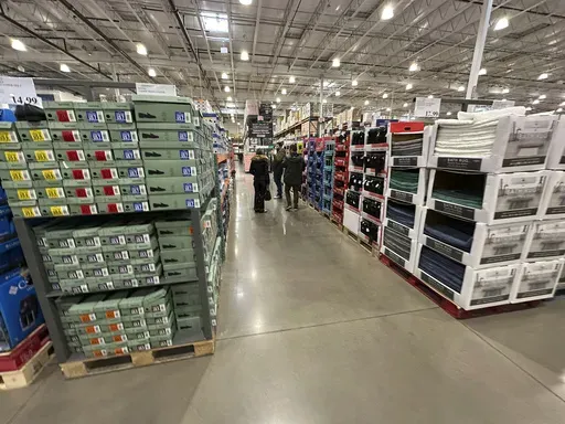 Shoppers make their ways down an aisle lined with clothing and shoes in a Costco warehouse Thursday, Jan. 23, 2025, in Sheridan, Colo. (AP Photo/David Zalubowski, File)
