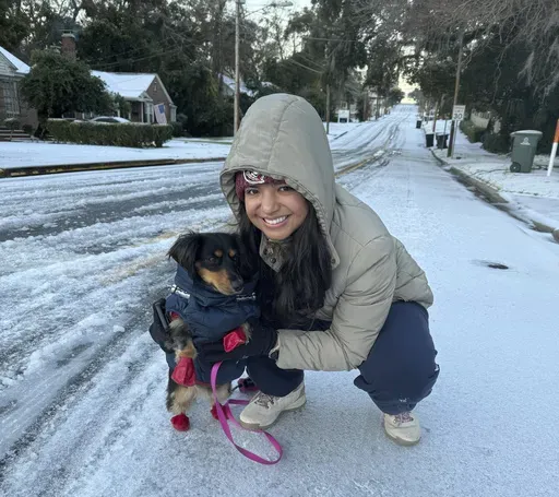 Lina Rojas prepares her dachshund Petunia with a warm vest and gloves for her first walk in snow, in Tallahassee, Fla., Wednesday, Jan. 22, 2025. (AP Photo/Kate Payne)