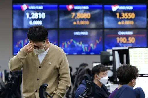 A currency trader holds his head at the foreign exchange dealing room of the KEB Hana Bank headquarters in Seoul, South Korea, Friday, Feb. 25, 2022. Asian shares rose Friday after U.S. stocks recovered toward the end of a wild trading day, as the world, including President Joe Biden, slapped sanctions against Russia for its invasion of Ukraine. (AP Photo/Ahn Young-joon)