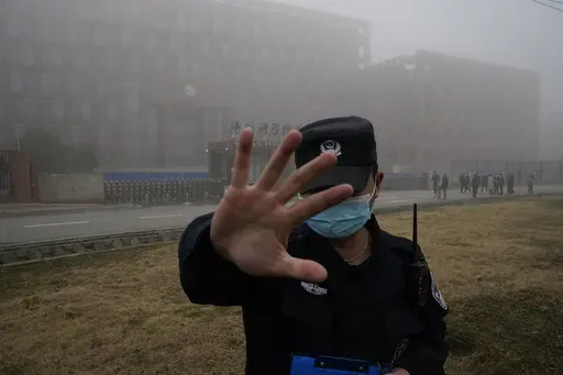A security person moves journalists away from the Wuhan Institute of Virology after a World Health Organization team arrived for a field visit in Wuhan in China's Hubei province on Feb. 3, 2021. The hunt for COVID-19 origins has gone dark in China. An AP investigation drawing on thousands of pages of undisclosed emails and documents and dozens of interviews found feuding officials and fear of blame ended meaningful Chinese and international efforts to trace the virus almost as soon as they began