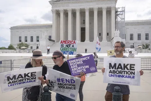 Katie Mahoney, left, and Rev. Patrick Mahoney, chief strategy officer for Stanton Healthcare, an Idaho-based pregnancy center that does not provide abortions, read the text of a Supreme Court decision outside the Supreme Court on Thursday, June 27, 2024, in Washington. The Supreme Court cleared the way Thursday for Idaho hospitals to provide emergency abortions for now in a procedural ruling that left key questions unanswered and could mean the issue ends up before the conservative-majority cour