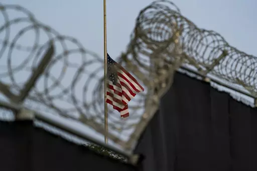 In this photo reviewed by U.S. military officials, a flag flies at half-staff in honor of the U.S. service members and other victims killed in the terrorist attack in Kabul, Afghanistan, as seen from Camp Justice in Guantanamo Bay Naval Base, Cuba, Aug. 29, 2021. The first U.N. independent investigator to visit the U.S. detention center at Guantanamo Bay said Monday, June 26, 2023, that the 30 men held there are subject “to ongoing cruel, inhuman and degrading treatment under international law