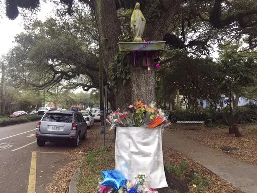 Flowers, balloons and Mardi Gras beads are placed at a makeshift memorial next to a bicycle lane in New Orleans on March 4, 2019. On Thursday, Dec. 15, 2022, a driver who was drunk when he struck nine bicycle riders near a Mardi Gras parade route in New Orleans in 2019, killing two, was re-sentenced to 65 years in prison — down from the 91 years he originally faced. (AP Photo/Kevin McGill, File)