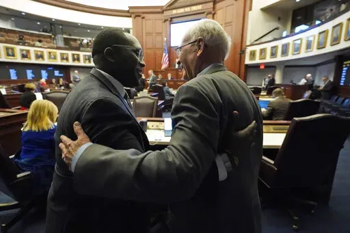 Florida Sen. Dennis Baxley, right, the sponsor of a bill, dubbed by opponents as the "Don't Say Gay" bill, hugs an opponent of the bill, Sen. Shevrin Jones, after the bill passed during a legislative session at the Florida State Capitol, Tuesday, March 8, 2022, in Tallahassee, Fla. (AP Photo/Wilfredo Lee)
