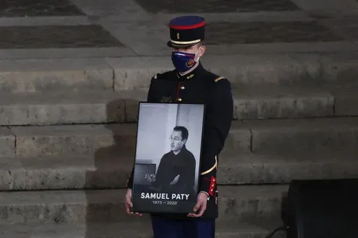 A Republican Guard holds a portrait of Samuel Paty in the courtyard of the Sorbonne university during a national memorial event, Wednesday, Oct. 21, 2020 in Paris. (AP Photo/Francois Mori, Pool, File)