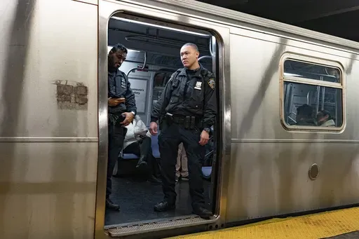 NYPD officers stand aboard a train at the West Fourth Street subway station, Saturday, Jan. 13, 2024, in New York. Prosecutors say a man who shot and critically wounded another man on a New York City subway train will not immediately be charged with a crime while prosecutors investigate whether the shooter acted justifiably in self-defense.(AP Photo/Peter K. Afriyie, File)