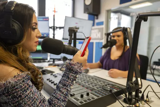 Melanie Nagy, left, and Szandi Minzari, hosts of Radio Dikh's women's show 'Zsa Shej', work together in a radio studio in Budapest, Hungary, Friday May 6, 2022. Intellectuals, broadcasters and cultural figures from Hungary’s Roma community have founded a radio station to reframe narratives and elevate the voices of their marginalized minority group. (AP Photo/Bela Szandelszky)