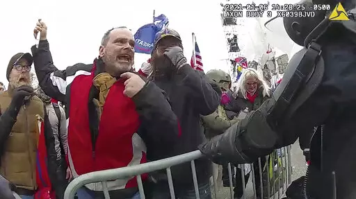 This still frame from Metropolitan Police Department body worn camera video shows Thomas Webster, in red jacket, at a barricade line at on the west front of the U.S. Capitol on Jan. 6, 2021, in Washington. More than 800 people across the U.S. have been charged in the Jan. 6 riot at the Capitol that left officers bloodied and sent lawmakers running in fear, and federal authorities continue to make new arrests practically every week (Metropolitan Police Department via AP)