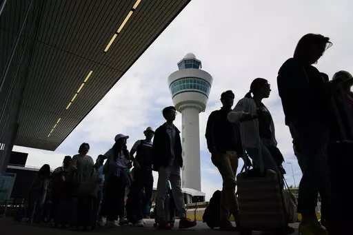 Travelers wait in long lines outside the terminal building to check in and board flights at Amsterdam's Schiphol Airport, Netherlands, Tuesday, June 21, 2022. After two years of pandemic restrictions, travel demand is back with a vengeance but airlines and airports that slashed jobs during the depths of the COVID-19 crisis are struggling to keep up. With the busy summer tourism season underway in Europe, passengers are encountering chaotic scenes at airports, including lengthy delays, canceled f