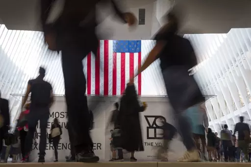 People walk past an American flag inside the Oculus, part of the World Trade Center transportation hub, at the start of a work day in New York, Sept. 11, 2019. American lore is full of tales of a nation built on the foundations of individualism. In reality, loneliness in America can be deadly. In May 2023, the U.S. surgeon general declared it an epidemic, saying that it takes as deadly a toll as smoking. (AP Photo/Wong Maye-E, File)