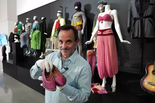 James Comisar holds a pair of shoes once used by actor Barbara Eden in the television show, "I Dream of Jeannie", Thursday, April 27, 2023, in Irving, Texas. A dizzying number of props, sets, and costumes from television shows beloved by generations of viewers will be sold at auction next month. The collection James Comisar has spent over 30 years amassing includes "The Tonight Show" set Johnny Carson gave him after retiring, the timeworn living room from "All in the Family," and the bar where S