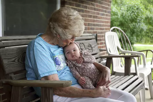 Tressie Corsi sits with her great great granddaughter Amelia Hollis on the porch of the house she has owned in Johnstown, Ohio, since 1972 to that she is giving up to make way for an Intel manufacturing plant during an interview Monday, June 20, 2022. Corsi and her husband raised four children and welcomed multiple generations of grandchildren and great-grandchildren, including some who lived right next door. (AP Photo/Paul Vernon)