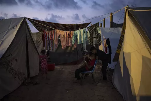Palestinian kids, who were displaced by the Israeli bombardment of the Gaza Strip, watch a phone in a UNDP-provided tent camp in Khan Younis, Gaza Strip, Wednesday, Nov. 1, 2023. While journalists' access to the war in Gaza is limited, a flood of video from all sorts of sources documents what is — and isn't — going on. (AP Photo/Fatima Shbair, File)