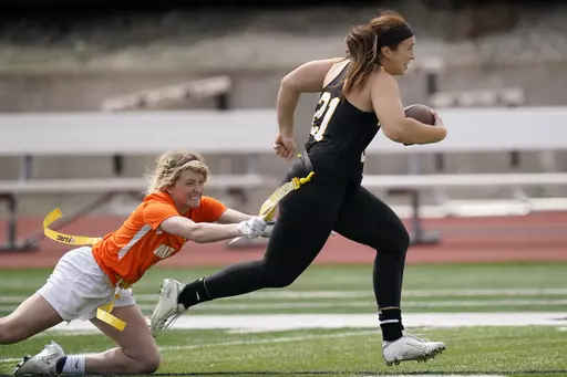 Ottawa quarterback Madysen Carrera (21) is tackled by Midland defender Casey Thompson, left, during an NAIA flag football game in Ottawa, Kan., Friday, March 26, 2021. Not surprisingly, the NFL is a big part of the push to make flag football an Olympic sport — at least for a one-off in Los Angeles. (AP Photo/Orlin Wagner, File)