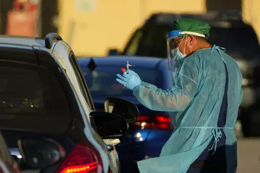 A health care worker tests people for COVID-19 at a drive-up testing center at Tropical Park, Wednesday, Dec. 29, 2021, in Miami. (AP Photo/Rebecca Blackwell)