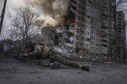 A Ukrainian police officer takes cover in front of a burning building in Avdiivka, Ukraine, Friday, March 17, 2023. The second year of Ukraine’s fight against Russia’s full-scale invasion brought no respite for Ukrainian soldiers or civilians. Associated Press photographers documented the past 12 months of death and destruction, agony and grief — as well as the glimpses of joy — that are staples of life during war. (AP Photo/Evgeniy Maloletka)