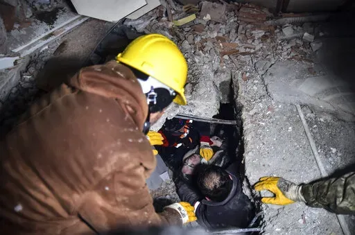 Emergency workers and medics rescue a woman out of the debris of a collapsed building in Elbistan, Kahramanmaras, in southern Turkey, Tuesday, Feb. 7, 2023. Rescuers raced Tuesday to find survivors in the rubble of thousands of buildings brought down by a 7.8 magnitude earthquake and multiple aftershocks that struck eastern Turkey and neighboring Syria. (Ismail Coskun/IHA via AP)