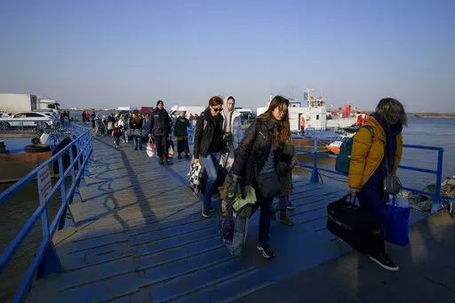 Refugees fleeing the war from neighbouring Ukraine walk after crossing the border by ferry at the Isaccea-Orlivka border crossing in Romania, Thursday, March 24, 2022. (AP Photo/Andreea Alexandru)