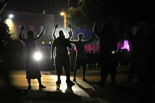 People raise their hands as police, trying to get them to disperse, move toward them during protests on Aug. 11, 2014 over the police shooting of Michael Brown in Ferguson, Mo. (AP Photo/Jeff Roberson, File)