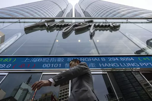 A pedestrian passes by the Hong Kong Stock Exchange electronic screen in Hong Kong, Wednesday, April 12, 2023. Asian shares were mostly higher Wednesday, as markets watched for key inflation data likely to influence the Federal Reserve's stance on interest rates. (AP Photo/Louise Delmotte)