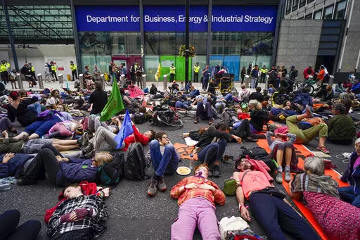 Demonstrators lay in front of the Department for Business, Energy and Industrial Strategy during a protest organized by the climate activists group Extinction Rebellion in London on Aug. 26, 2021. The U.K. division of climate change protest group Extinction Rebellion says its activists would temporarily stop blocking busy roads, gluing themselves to buildings and engaging in other acts of civil disobedience because such methods have not achieved their desired effects. (AP Photo/Alberto Pezzali, 