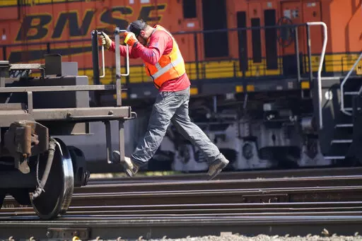 A worker rides a rail car at a BNSF rail crossing in Saginaw, Texas, Wednesday, Sept. 14, 2022. Business and government officials are preparing for a potential nationwide rail strike at the end of this week while talks carry on between the largest U.S. freight railroads and their unions. (AP Photo/LM Otero)