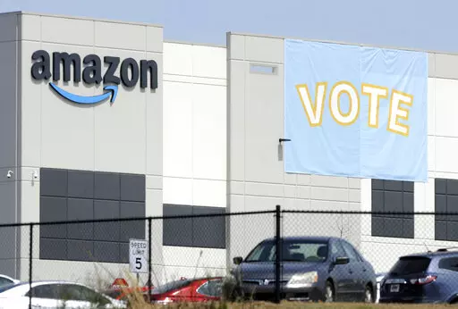 A banner encouraging workers to vote in labor balloting is shown at an Amazon warehouse in Bessemer, Ala., on Tuesday, March 30, 2021. Amazon workers and organizers in Bessemer, Alabama, are making door-to-door house calls, sporting pro-union T-shirts and challenging anti-union messaging by Amazon-hired consultants as they try to convince their peers for the second time to unionize their warehouse. The union election starts Friday, Feb. 4, 2022, by secret ballot (AP Photo/Jay Reeves, File)