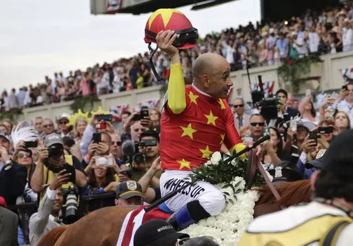 Jockey Mike Smith tips his helmet to the crowd as he rides Justify to the winner's circle after winning the 150th running of the Belmont Stakes horse race and Triple Crown on June 9, 2018, in Elmont, N.Y. Earlier in 2023, horse racing was rocked by the deaths less than six weeks apart of two young jockeys, 23-year-old Avery Whisman and 29-year-old Alex Canchari, each of whom killed himself. A friend of Whisman's, Triple Crown-winning rider Mike Smith has over three decades seen similar tragedies