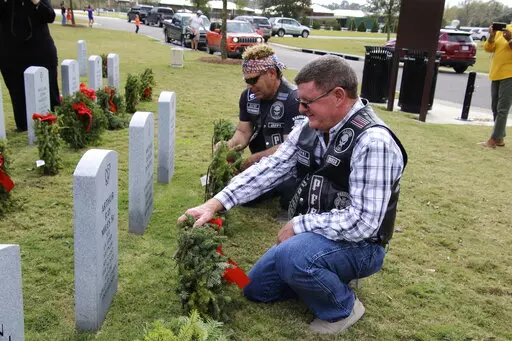 Dean Luntsford and Joe Chapman of the Punishers Law Enforcement Motorcycle Club of Jennings pause to place fresh wreaths Saturday on graves at the Southwest Louisiana Veteran Cemetery in Jennings, La. Nearly 200 wreaths were placed on the graves by friends, family and volunteers as part of Wreaths Across America Day. (Doris Maricle/American Press via AP)