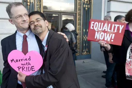 John Lewis, left, and Stuart Gaffney embrace outside San Francisco's City Hall shortly before the U.S. Supreme Court ruling cleared the way for same-sex marriage in California, June 26, 2013. The U.S. Census Bureau on Tuesday, June 11, 2024, reported that same-sex spouses were typically younger, had more education and were more likely to be employed than those in opposite-sex marriages. (AP Photo/Noah Berger, File)