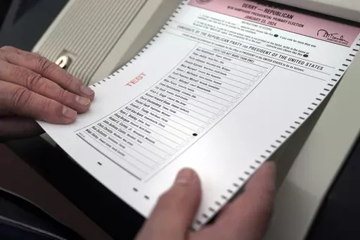 Nick Zaharias of Derry, N.H., a public witness, loads a test ballot into a vote counting machine while testing machines before the New Hampshire primary, at the Derry Municipal Center, Tuesday, Jan. 16, 2024. (AP Photo/Charles Krupa)