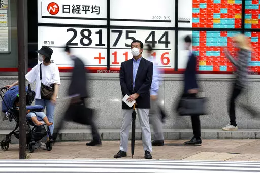 A person wearing a protective mask stands in front of an electronic stock board showing Japan's Nikkei 225 index at a securities firm Friday, Sept. 9, 2022, in Tokyo. Asian benchmarks rose Friday, cheered by gains on Wall Street as comments from the Federal Reserve chairman assured markets on the expected rate rise.(AP Photo/Eugene Hoshiko)