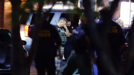 Police gather at the Aldi on New Bern Avenue in Raleigh, N.C., Thursday, Oct. 13, 2022. A gunman opened fire along a walking trail in North Carolina's capital city on Thursday, killing five people before leading police on an hours-long manhunt that forced residents across multiple neighborhoods to take shelter in their homes. (Ethan Hyman/The News & Observer via AP)