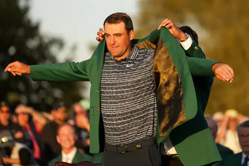 Hideki Matsuyama, of Japan, helps Scottie Scheffler put on the green jacket after winning the 86th Masters golf tournament on Sunday, April 10, 2022, in Augusta, Ga. (AP Photo/Jae C. Hong)