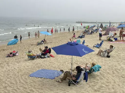 Beachgoers sit on chairs and under umbrellas at Ocean Grove, N.J., beach on Sunday, May 26, 2024. As the temperature heats up and summer approaches, small business owners may be considering offering summer hours, such as an early release on Fridays, for employees to help combat burnout. (AP Photo/Tassanee Vejpongsa, File)