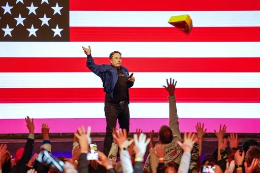 Elon Musk tosses a cheesehead during a town hall Sunday, March 30, 2025, in Green Bay, Wis. (AP Photo/Jeffrey Phelps)