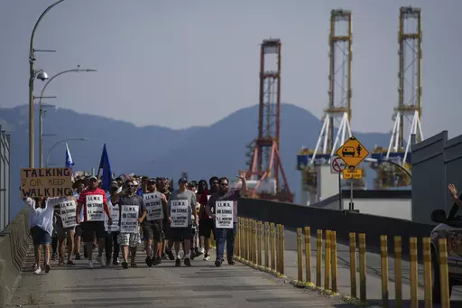 Striking International Longshore and Warehouse Union Canada workers march to a rally as gantry cranes used to load and unload cargo containers from ships sit idle at port, in Vancouver, on Thursday, July 6, 2023. (Darryl Dyck /The Canadian Press via AP)